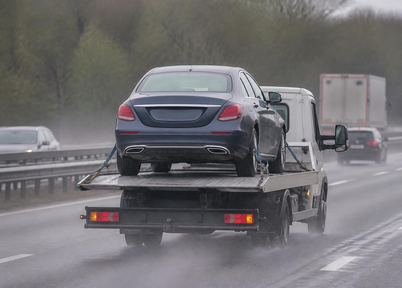 Flatbed transporter carrying two cars on a motorway